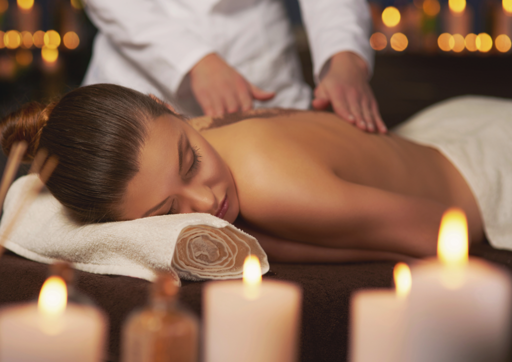 Relaxed woman in spa - aromatherapy - candles - massages - hands massaging - candle lights in the background